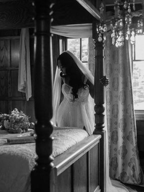 Dreamy black and white candid bridal portrait framed by the drapes of a four-poster bed in a historic Toronto bridal suite.