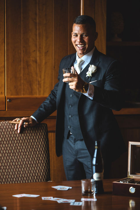 A formal portrait of the groom, dressed in a sharp suit, holding a drink and looking directly at the camera, conveying the sophistication of a Niagara wedding.