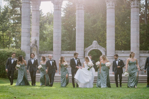 Scenic wide-angle shot of a large wedding party posing together at the base of the towering Greek Theatre columns.