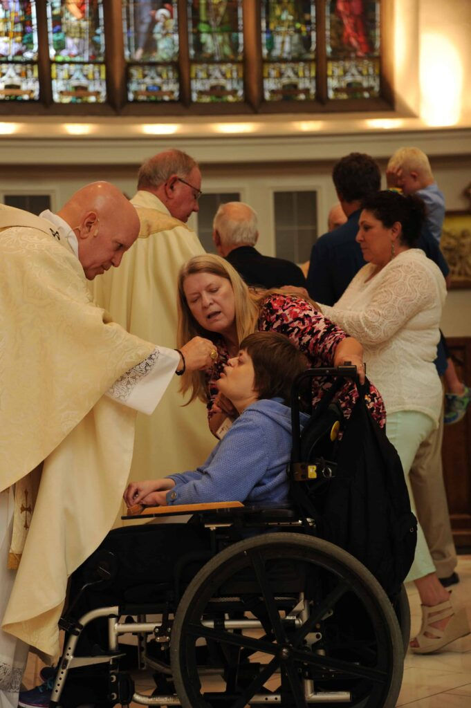 Archbishop Aquila hosts gives a participant in the Special Education Mass Holy Communion. Students and their families were all invited to attend. (Photo by Bernard Grant/Denver Catholic)