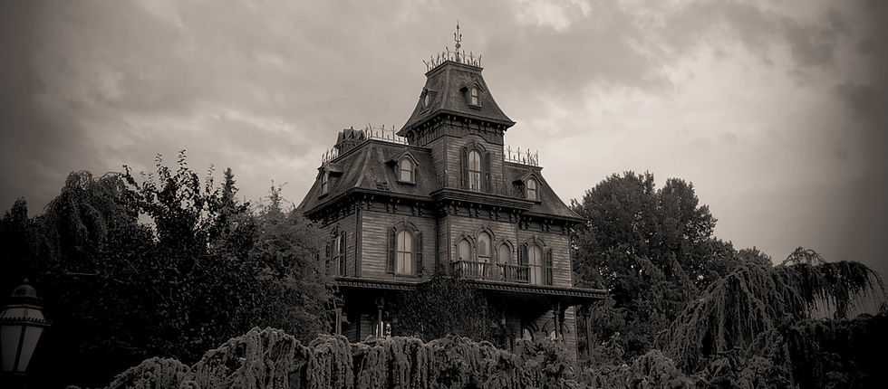Spooky Victorian mansion on a hill, framed by dark trees under a cloudy sky, with a moody black-and-white tone.