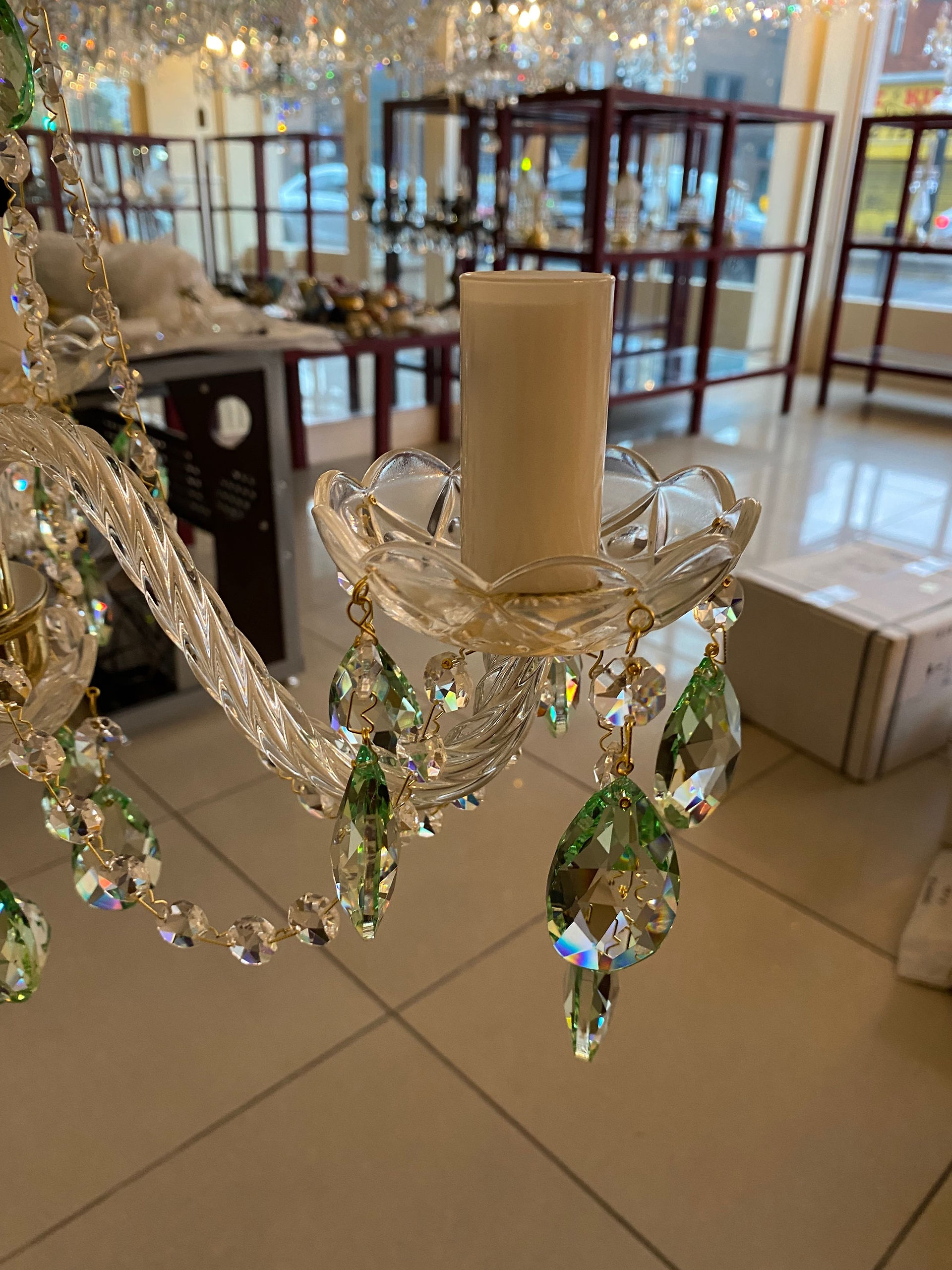 Farrah-3-5005 is an elegant small chandelier featuring 30% PbO Bohemian coloured crystal. This exquisite piece boasts rope twist glass arms, ornate glass bobeches, and opaque glass candle holders. Suitable for standard ceiling heights and small to medium rooms, it is dressed in oval lead crystals, pastel green (5005), and delicate chains that sparkle beautifully, creating a captivating display.