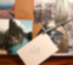 A collage is half finished. There is a background of a few nature images glued onto cardboard, and then there is a pen and the back of a photo which has written on it: "I will hike the Fundy Footpath"