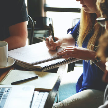 Menschen sitzen am Tisch und arbeiten in einem World-Café