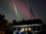 House with flag under green and purple aurora