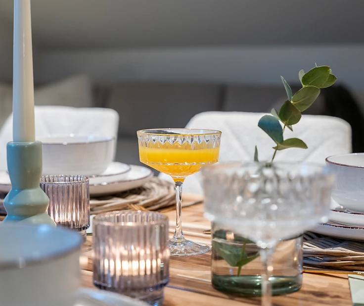 Elegante gedekte eettafel met wijnglazen, kaarsen en glazen sap in Huys van Haeghe