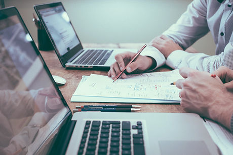 Business owner reviewing financial documents and laptop during tax planning session