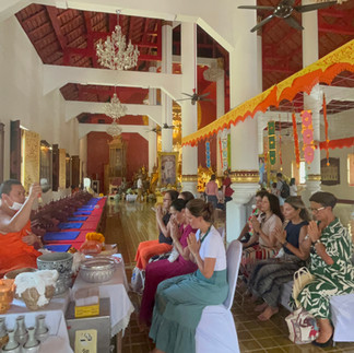 Interior de templo budista, pessoas sentadas em cerimônia.