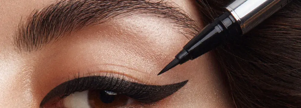 Kalıcı eyeliner uygulaması sırasında müşterinin göz kapağına yakın çekim.