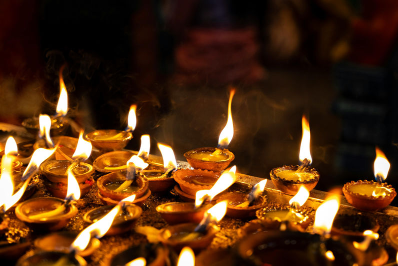 Glowing oil lamps during a Buddhist ceremony in Sri Lanka with warm spiritual atmosphere and cultural traditions.