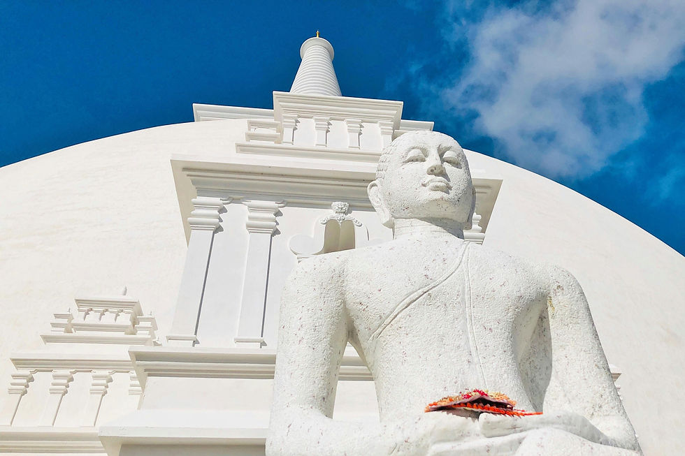 White Buddhist stupa and Buddha statue at a temple in Anuradhapura, Sri Lanka