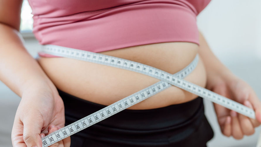 Persoană supraponderală care își măsoară talia. Imagine reprezentativă pentru obezitatea de tip central și riscurile asociate cu grăsimea viscerală