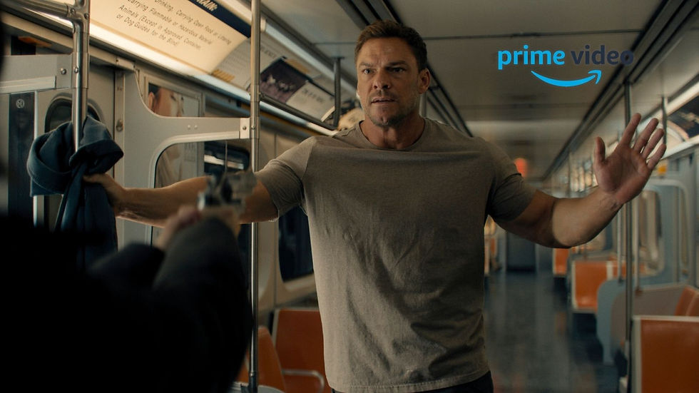 Man on a subway car raises his hands as a gun is aimed at him; Prime Video logo appears, tense scene with orange seats.