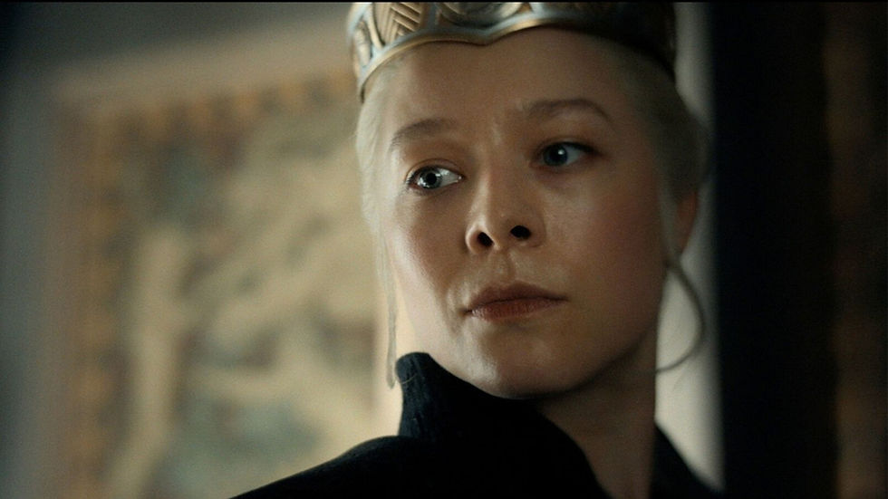 Close-up of a woman wearing a crown and black clothing, staring seriously against a blurred indoor background.