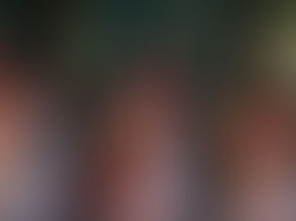 Five women in torn white dresses, smeared with blood, walk cautiously through a dim, ornate room. Their expressions are tense and determined.