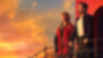Two people stand on a balcony, gazing at a colorful sunset. The sky is a blend of orange and yellow hues, creating a serene mood.