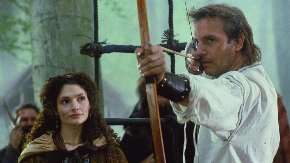 Man in white tunic draws a bow and arrow beside a woman in a forest camp, both tense and focused.