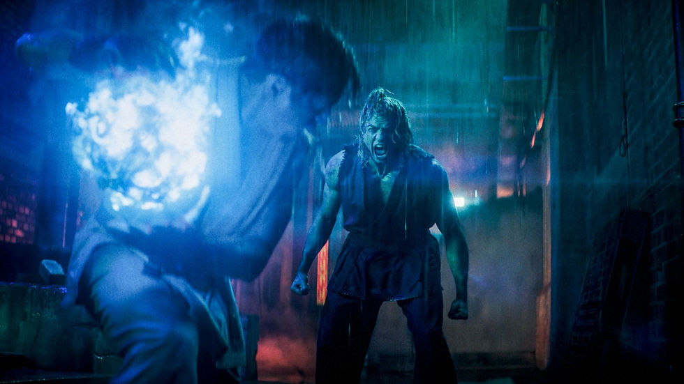 Street Fighter (2026): Two fighters in a rain-soaked neon alley, one screaming as a bright blue energy blast lights the scene.