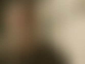 A man in a green shirt looks up behind prison bars, casting a thoughtful expression in a dimly lit cell with a pale background.