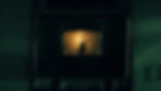 A dark oven with a silhouette of a hand inside, backlit by an eerie yellow light. The oven has vintage style knobs and handles.