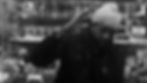 Black-and-white image of a man in a knit beanie saluting inside a convenience store, with cigarette packs and Red Man display behind him.