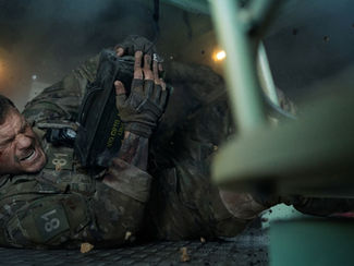Soldier in camo struggles on a metal floor, holding a black box amidst sparks and debris. Intense expression; text reads "100 CRTG."