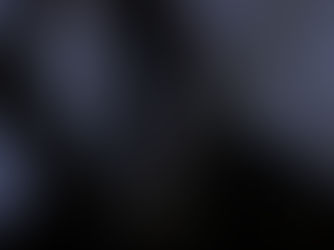 Masked figure in black robe holding knife indoors, against a blue-tinted background. The mask has a white, ghost-like face, evoking fear.