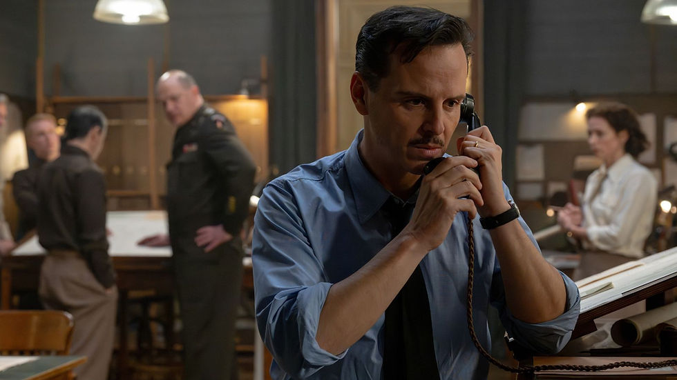 Tense man in blue shirt and tie speaks on a desk phone in a dim office, with blurred coworkers and warm lights behind him.