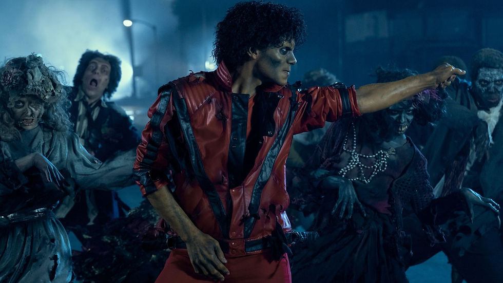 A person in a red and black jacket leads a group of zombie dancers in an eerie, foggy nighttime scene, expressing intensity and drama.