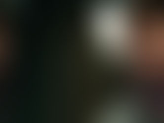 A man with short brown hair and a gray shirt looks intensely into a mirror, reflecting his serious expression. The background is blurred.