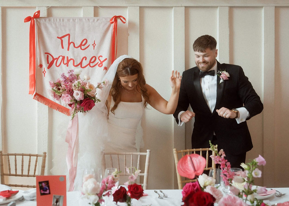 stylish bride and groom arriving at their top table, styled with beautiful, pink and red wedding flowers