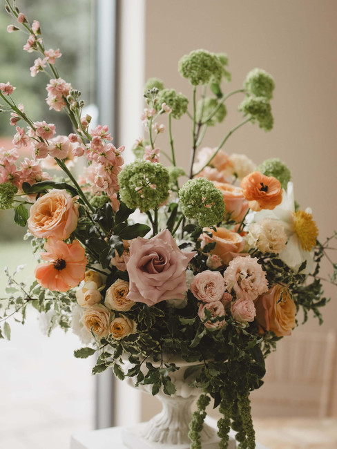 textural wedding ceremony urn flowers in peach, pink, green and yellow colour palette