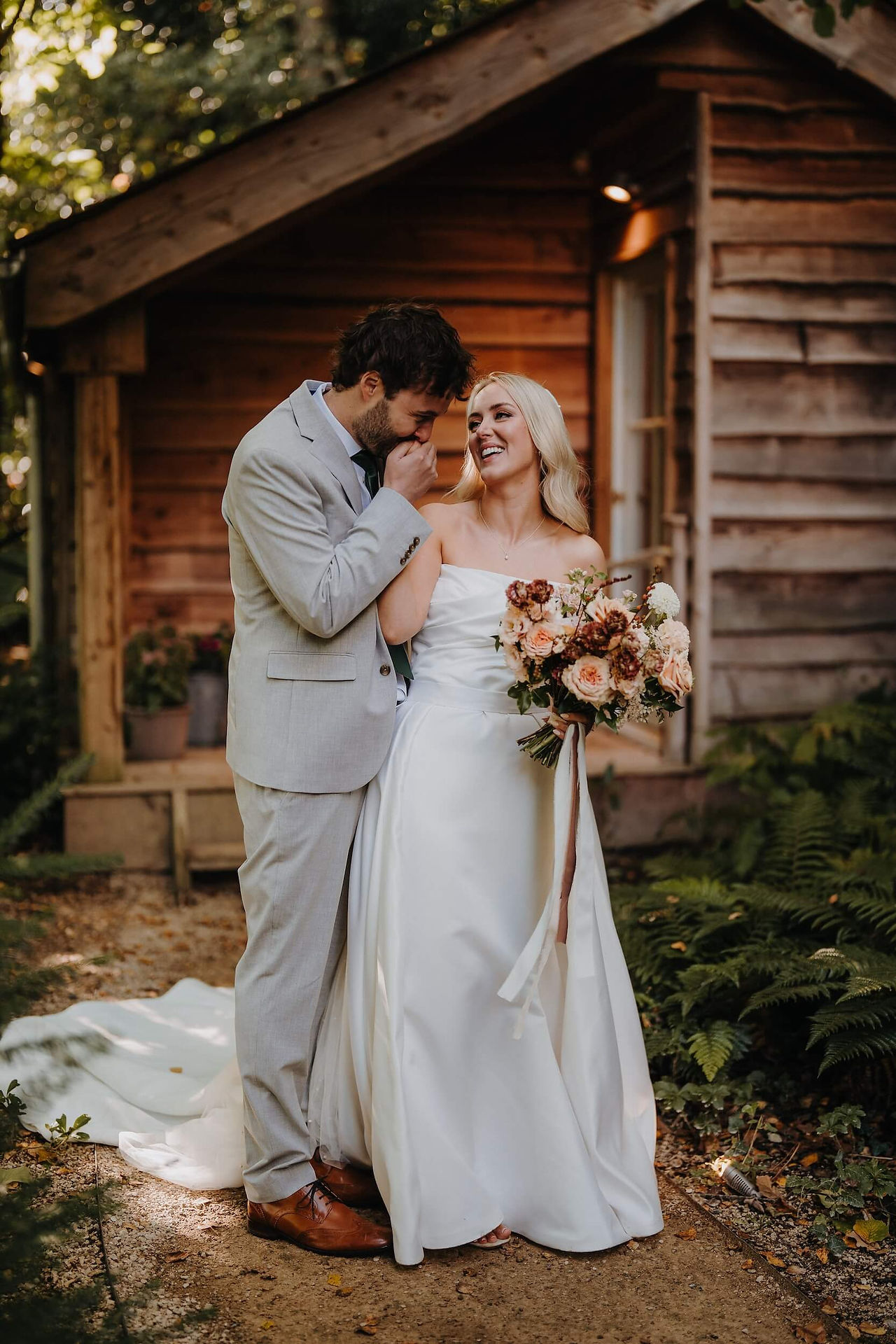 bride and groom posing for photos, with a beautiful bridal bouquet in ivory, peach, beige and brown colour palette