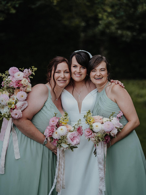 bride and her bridesmaids holding their bouquets and smiling