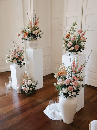 modern ceremony flowers at Hinwick House, consisting of beautiful pastel flowers dressing minimalistic plinths