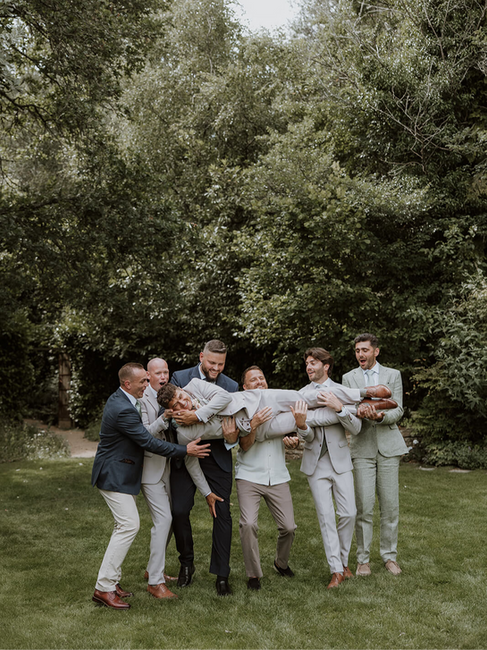 groomsmen carrying the groom in their arms and having fun