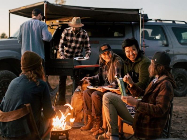a group of young people sitting around a campfire