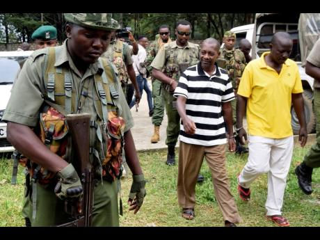 Cult preacher Pastor Paul Nthenge Mackenzie of the Good News International church, foreground centre, and some of his helpers arrive at the Shanzu Law Courts under tight security, in Mombasa, Kenya, Thursday, August 10, 2023. (Credit: Jamaica Gleaner Authors AP)