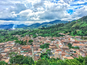Aerial view of Jardín, Antioquia, Colombia, showing red-tiled rooftops, cathedral, and surrounding Andean mountains.