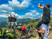 Group of motorcyclists posing with bikes on a ridge overlooking Colombian Andes mountains.