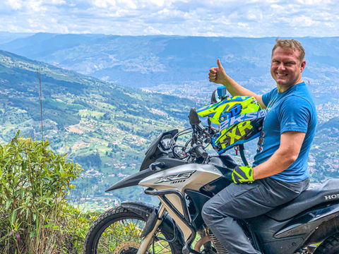 Man riding Honda XRE300 motorcycle on country road in Colombia.