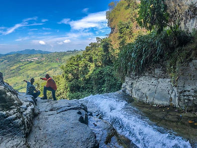 Two travelers looking out over the landscape from the entrance of a cave. 