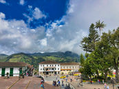Plaza of Sonsón, Antioquia with colonial architecture and Andes mountains in background, Colombia motorcycle tour stop.
