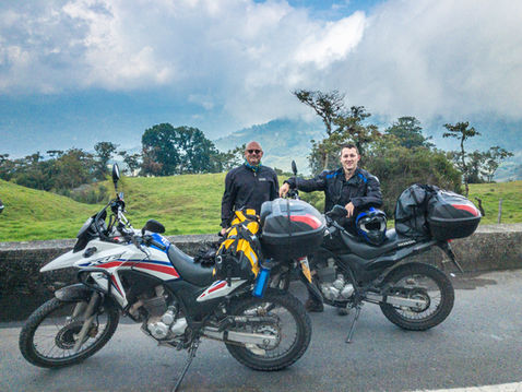 Two Honda XRE300 rentals with luggage in a Colombian cloud forest, ready for a multi-day tour.