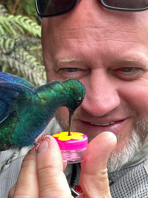 Rider hand-feeding a hummingbird on a Colombia motorcycle adventure.
