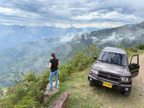 Mitsubishi Montero iO 4x4 rental parked at a mountain viewpoint in Colombia with a traveler enjoying the Andes landscape.