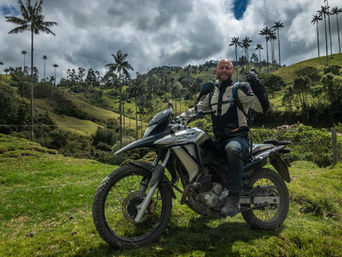 Rider posing with motorcycle in Cocora Valley’s wax palm forest.