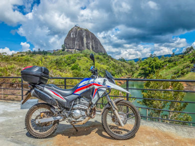 Honda XRE300 rental at viewpoint with El Peñol rock and the Guatapé reservoir.