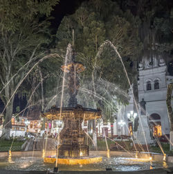 Night photo of lit fountain in Colombian town square during motorcycle trip.