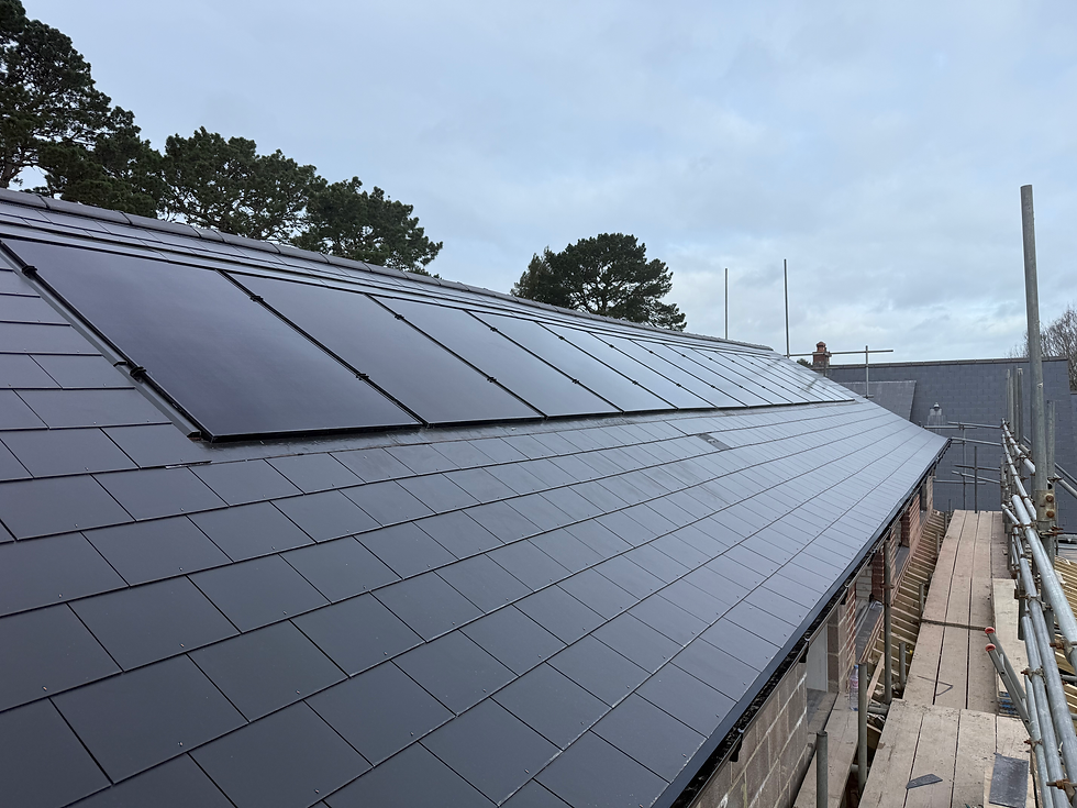 A wide shot of a grey tiled roof fitted with several sleek black solar panel units
